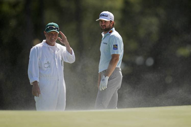 Cameron Young and his caddie Steve Underwood watch sand blow across the green on the 18th hole during second round at the Masters golf tournament at Augusta National Golf Club Friday, April 12, 2024, in Augusta, Ga. (AP Photo/Ashley Landis)