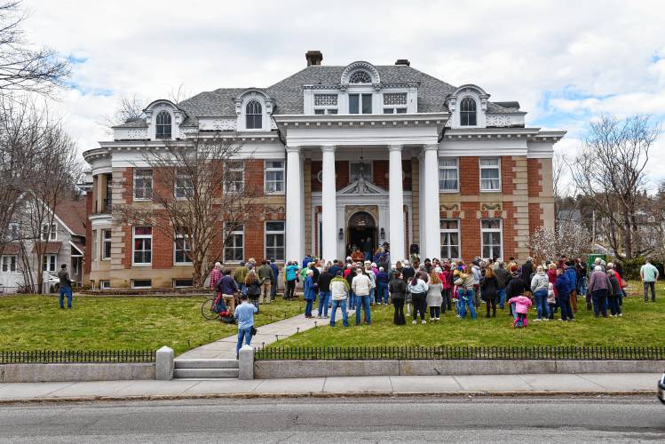 People gather on the front lawn to toast the ribbon-cutting of the renovated Revival Wheeler Mansion, which owner Cynthia Butler has been restoring.