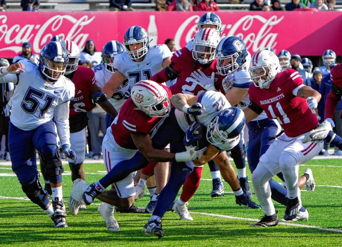 UMass players tackle UConn running back Victor Rosa (22) during the Minutemen’s 31-18 loss on Saturday at McGuirk Alumni Stadium in Amherst.