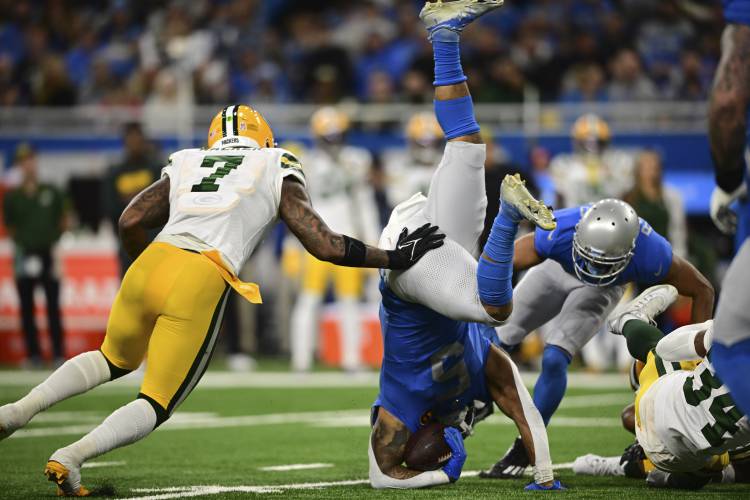 Detroit Lions running back David Montgomery (5) flips in front of Green Bay Packers linebacker Quay Walker (7) during the first half of an NFL football game, Thursday, Nov. 23, 2023, in Detroit. (AP Photo/David Dermer)