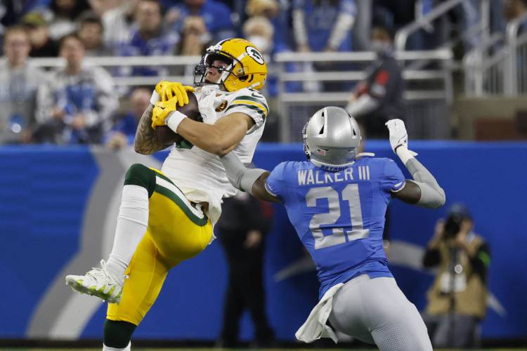 Green Bay Packers wide receiver Christian Watson (9) defended by Detroit Lions safety Tracy Walker III (21), catches a pass during the first half of an NFL football game, Thursday, Nov. 23, 2023, in Detroit. (AP Photo/Duane Burleson)
