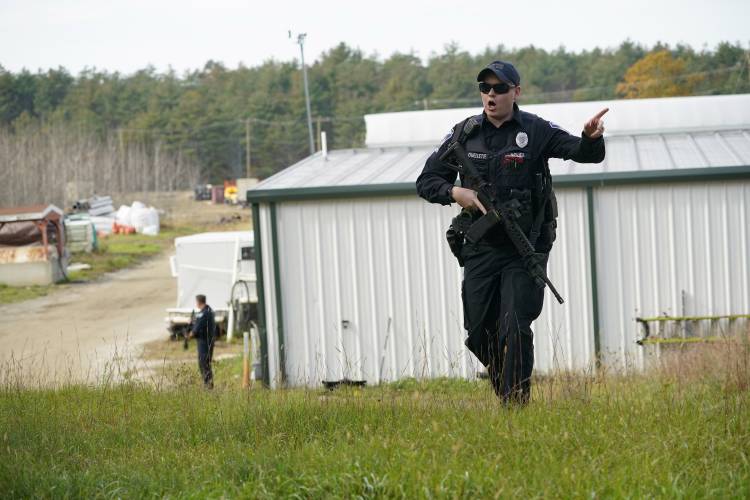 A police officer gives an order to the public during a manhunt at a farm for the suspect in this week's deadly mass shootings, Friday, Oct. 27, 2023, in Lisbon, Maine. Police are still searching for the man who killed at least 18 in separate shootings at a bowling alley and restaurant in Lewiston on Wednesday. (AP Photo/Robert F. Bukaty)