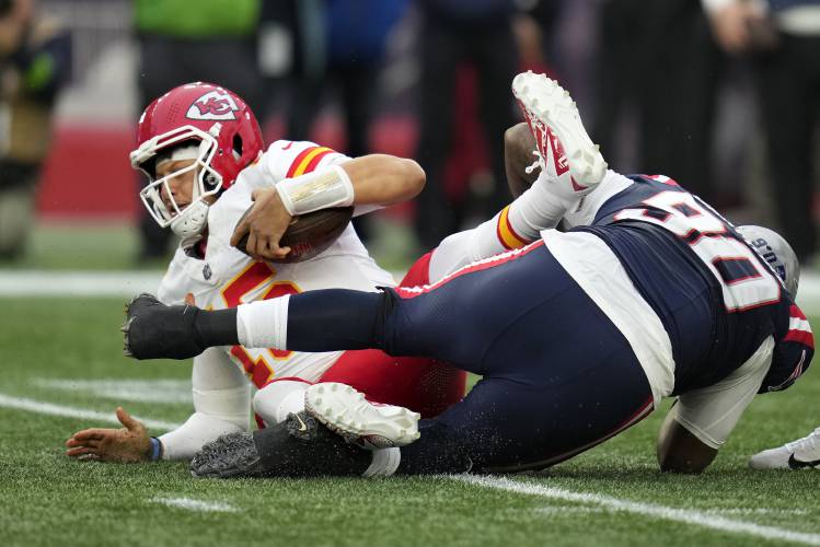 Kansas City Chiefs quarterback Patrick Mahomes, left, is sacked by New England Patriots defensive tackle Christian Barmore, right, during the first half Sunday in Foxborough.