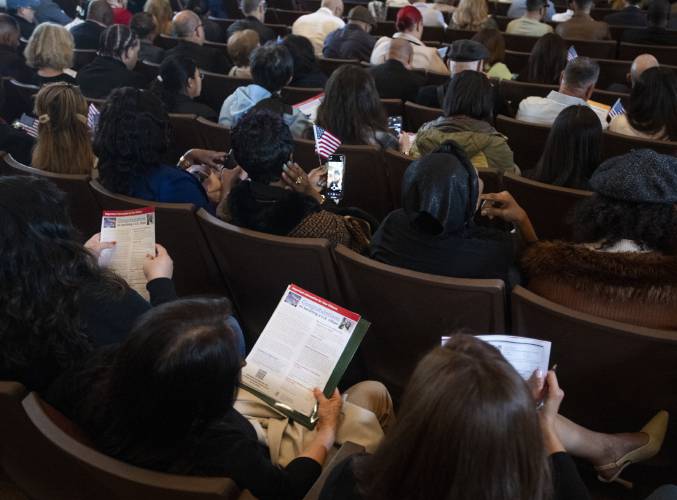 New American citizens read a handout before a naturalization ceremony at Bowker Auditorium, Tuesday, in Amherst.