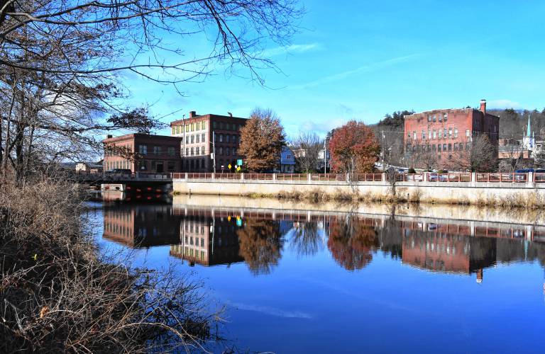 Buildings in Orange are reflected in the Millers River on a calm day.