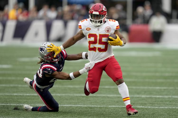 Kansas City Chiefs running back Clyde Edwards-Helaire (25) tries to elude New England Patriots cornerback Alex Austin (28) during the second half of an NFL football game, Sunday, Dec. 17, 2023, in Foxborough, Mass. (AP Photo/Charles Krupa)