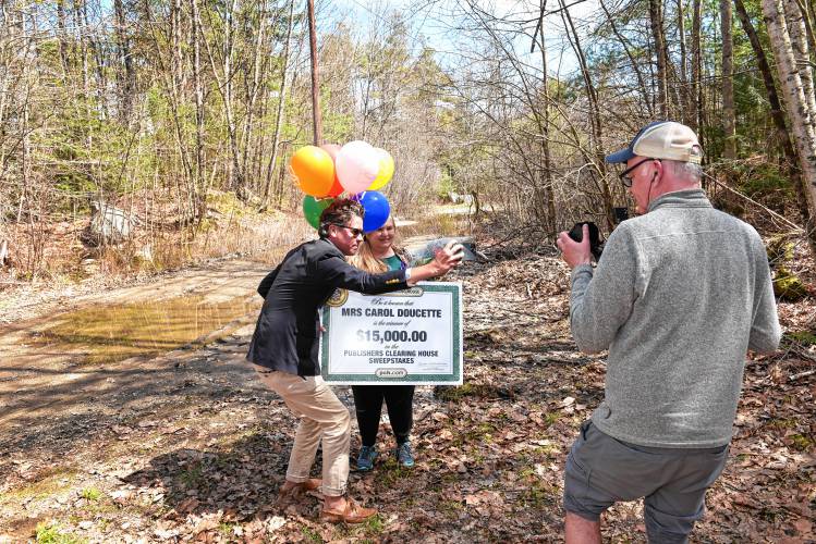 Carol Doucette of Royalston was surprised by Howie Guja, left, of Publishers Clearing House Sweepstakes with news that she was a winner posing for selfies and video next to the moat that prevented the usual doorbell ring presentation.
