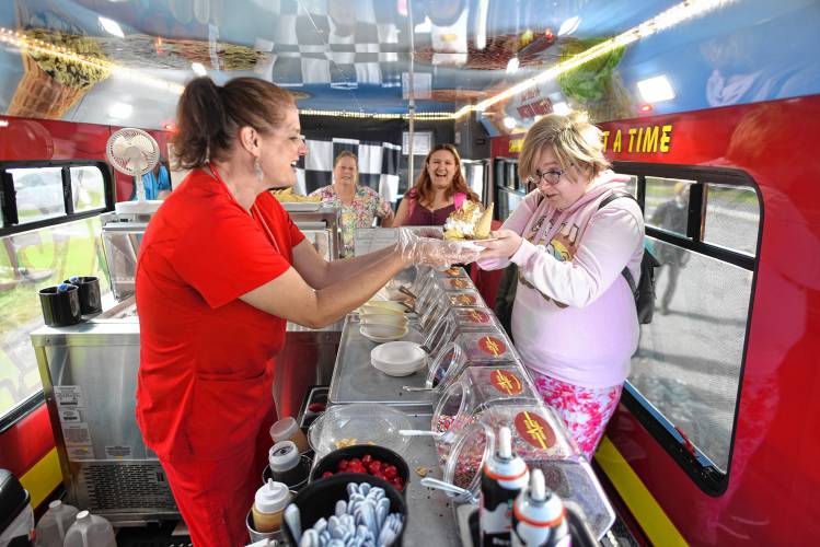 Addie Stiles of Ice Cream Emergency gives a waffle cone sundae to Greenfield Community College student Holly Tetreault of Greenfield. Next in line is student Isabelle Botelho of South Deerfield. GCC was celebrating increased enrollment on Wednesday with the free frozen treats. 