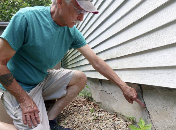 Ken Fisher points to one of the cracks in the foundation of his home in Vernon, Conn., July 1, 2019. 