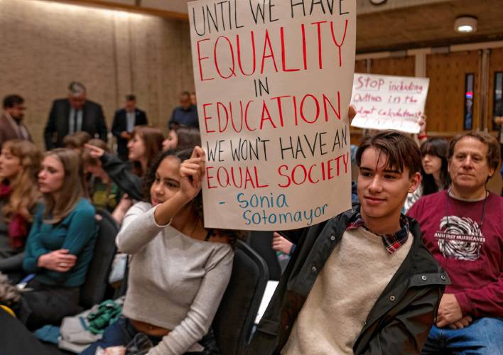 Violet Holcombe and Noah Ferris, Amherst Regional High School students, hold a sign inside the UMass Campus Center where a hearing of the Joint Committee on Ways and Means took place Monday. 